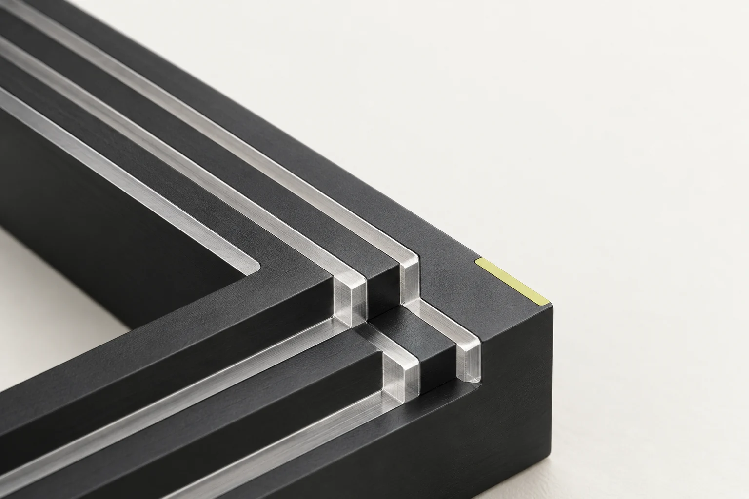 Three machined aluminium channels meeting at a precise stepped junction on a pale mineral background.